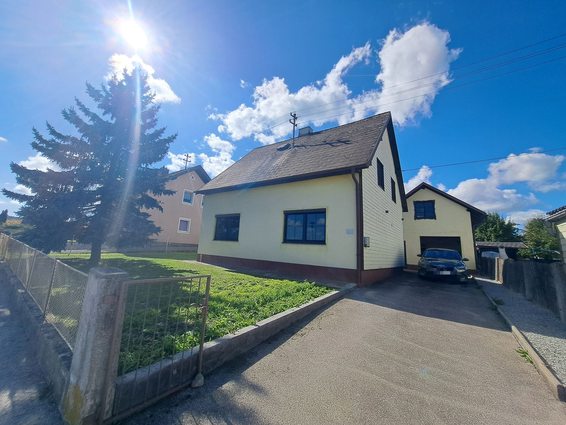 Einfamilienhaus mit Vorgarten, Zufahrt und Garage von der Straße aus