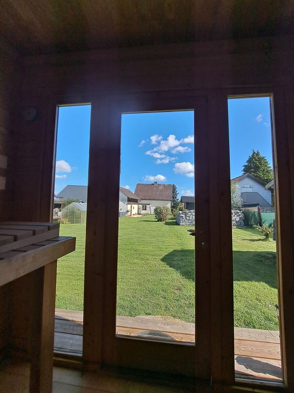 Blick aus der Sauna durch die Glastür in den Garten