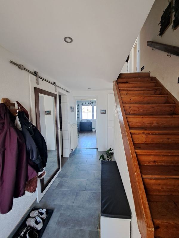 Gefliester Vorraum mit Garderobe und Holzstiege